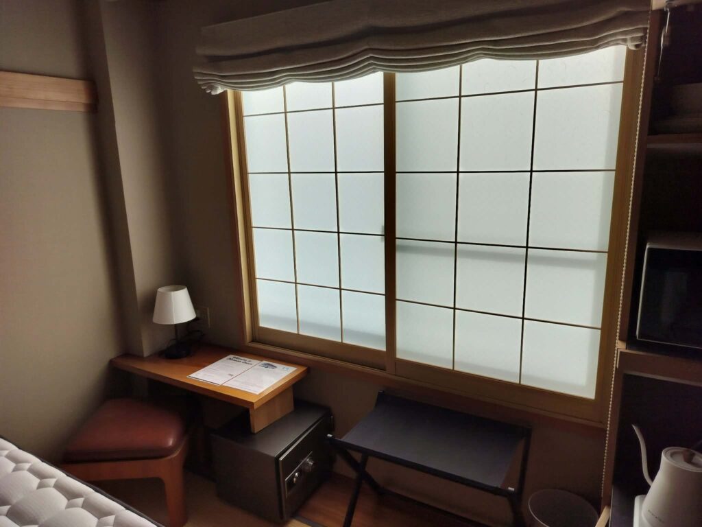 ROOMS Room 303: writing desk with lamp, in-room safe and luggage rack under a shoji-style window